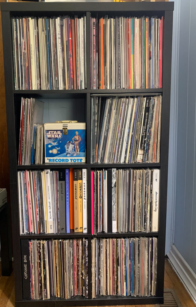 A set of shelves (4 high) filled with records. A Star Wars-themed "record tote" is on display on the 3rd shelf.